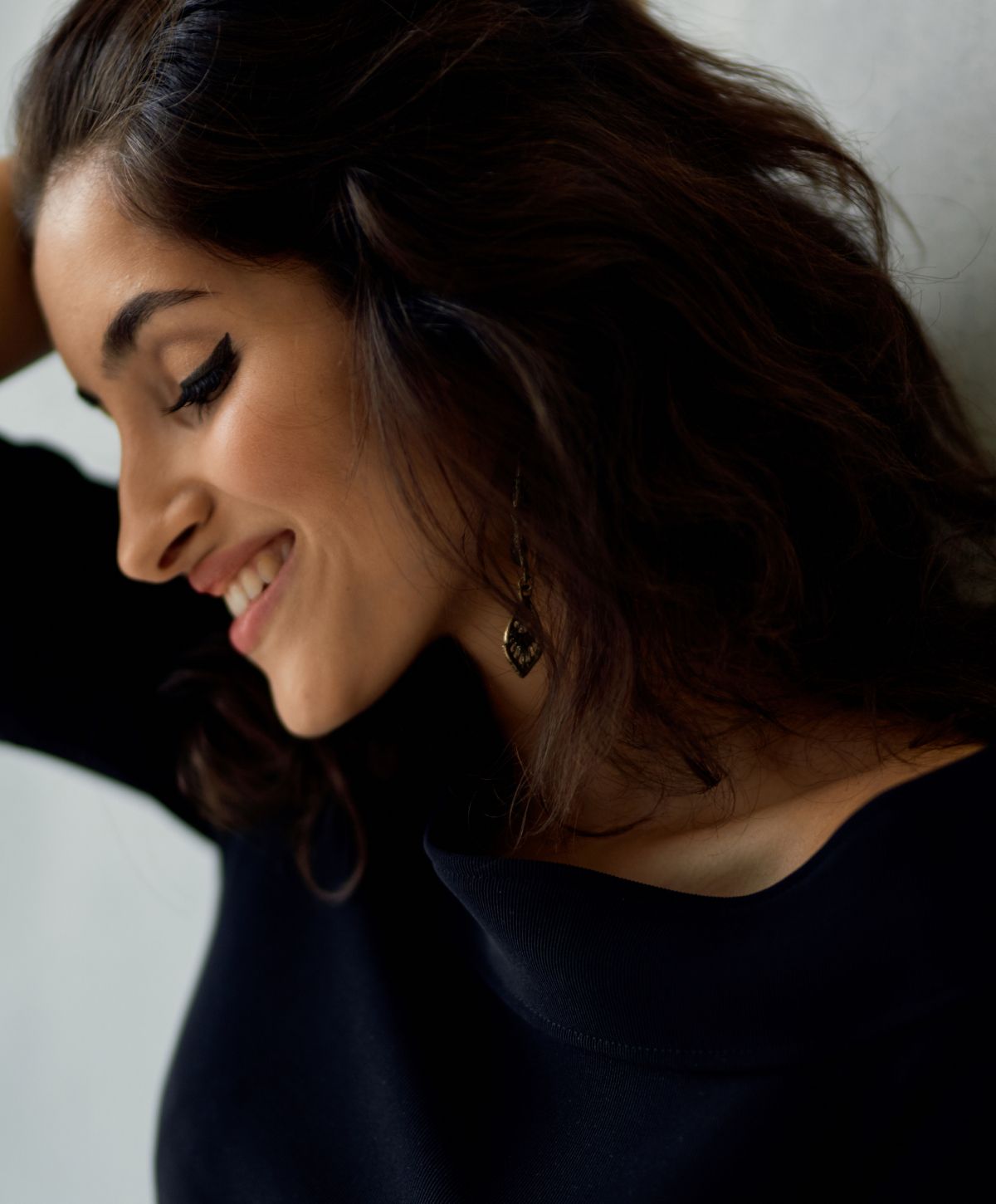 Woman smiling with dark hair and earrings.