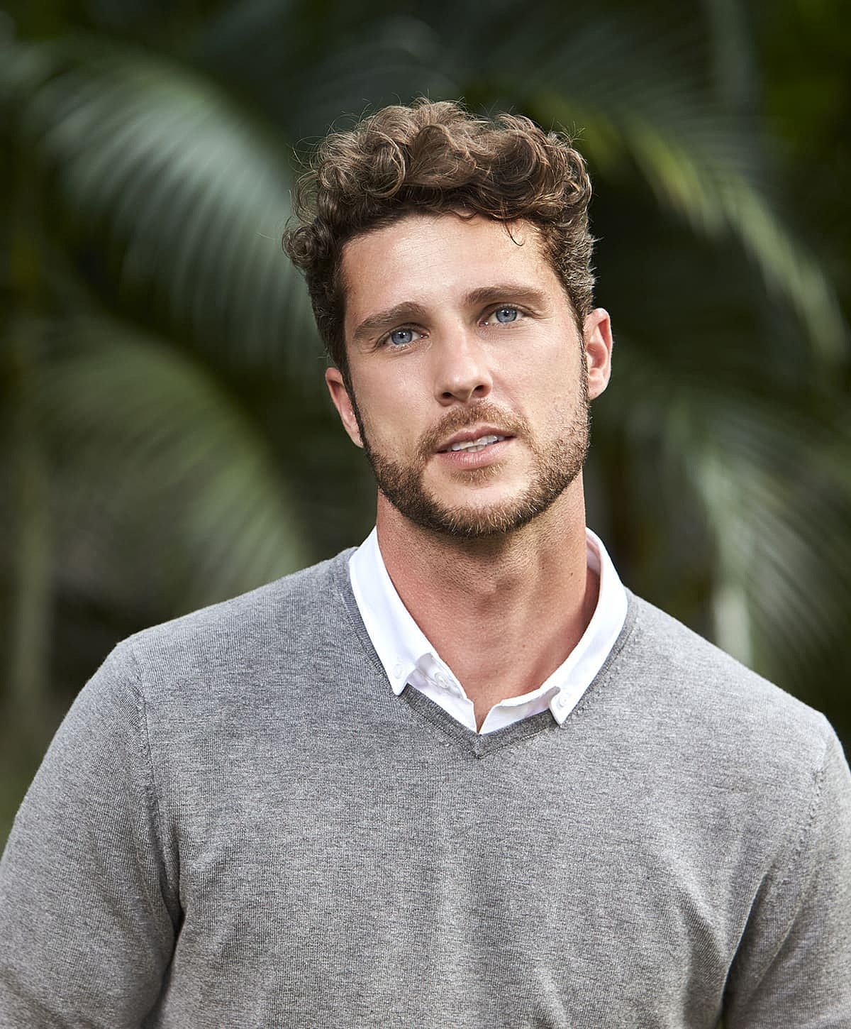 Young man in gray sweater against natural background.