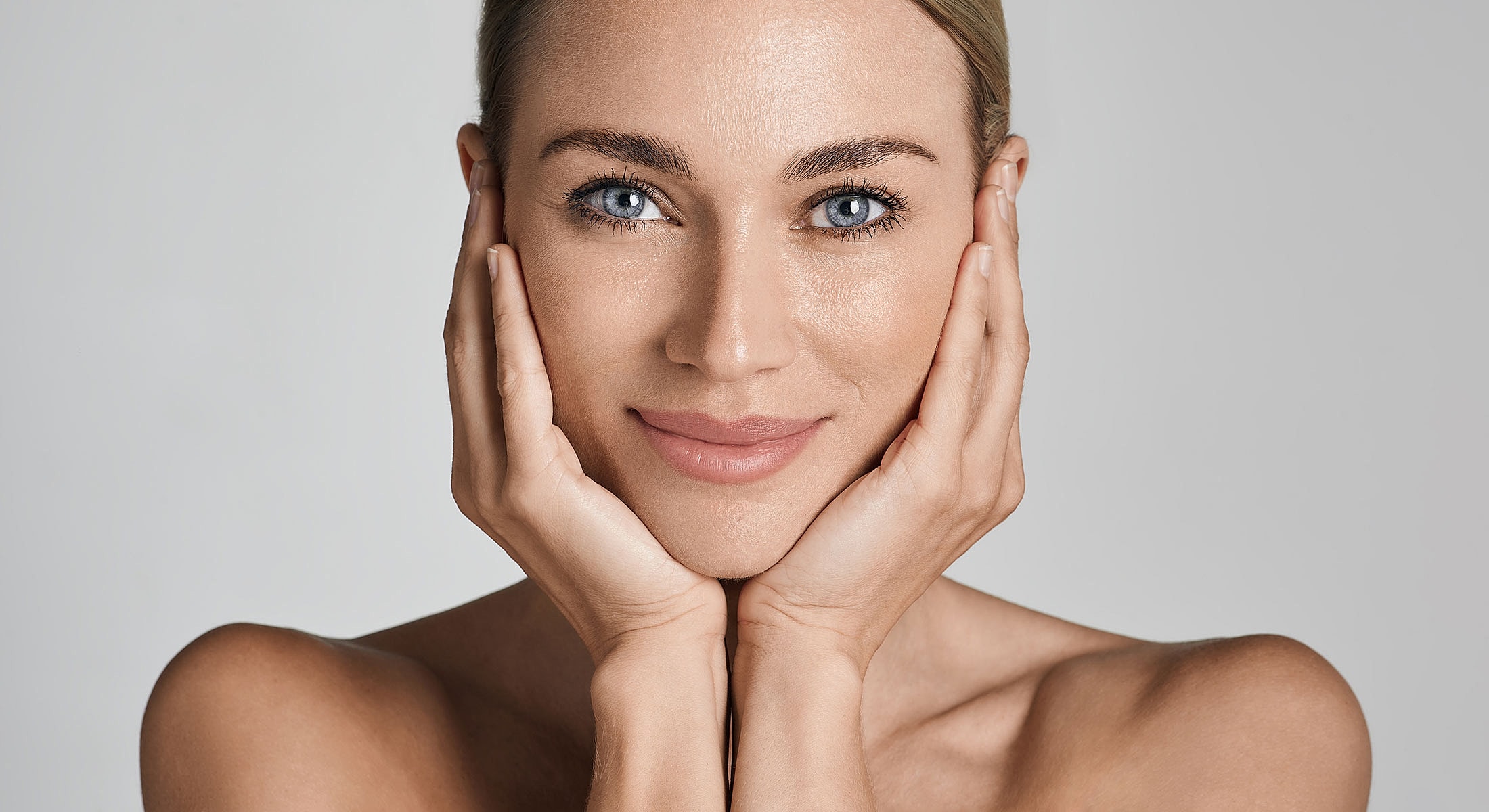 Smiling woman with blue eyes and hands on face