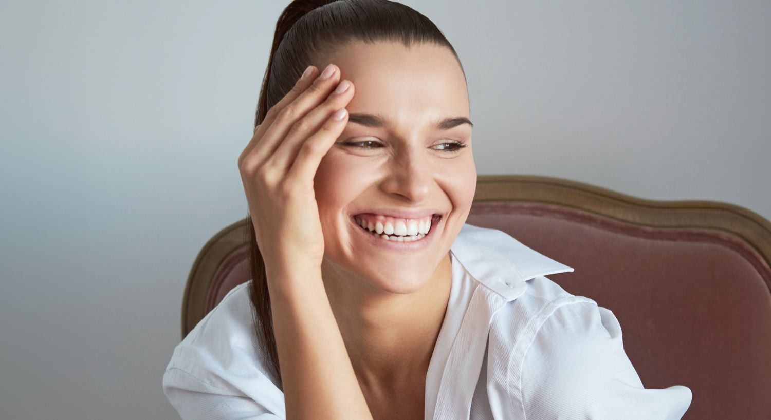 Smiling woman wearing a white shirt, joyful expression.